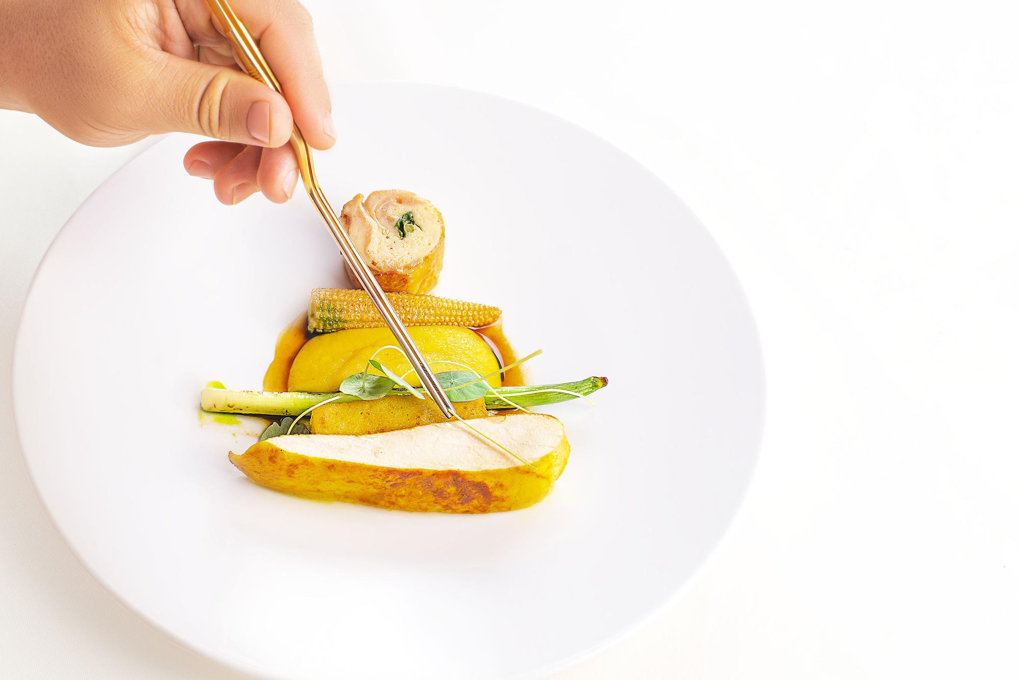 Hands plating a colorful main course